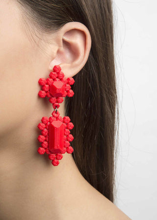 Red beaded earrings worn by a person on a white background