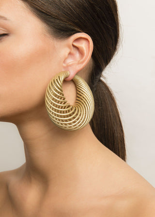 Gold hoop earring worn by a model against a neutral background