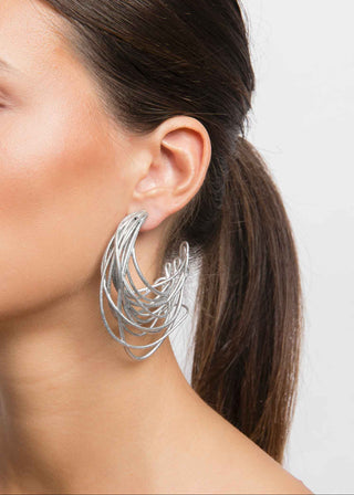 Silver hoop earrings worn by a person with a neutral background