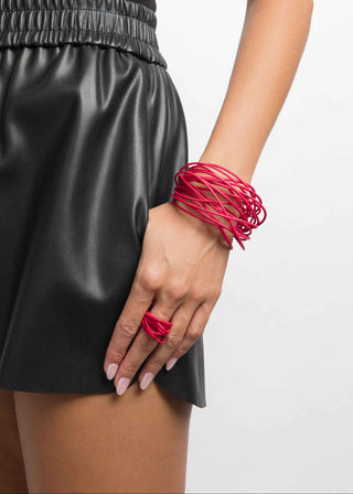 Person wearing a black leather skirt and red accessories on a white background