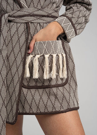 Textured fabric with tassels and a belt on a neutral background