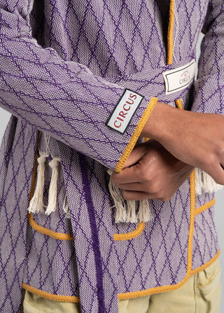 Purple textured garment with yellow accents and a visible brand label on a gray background
