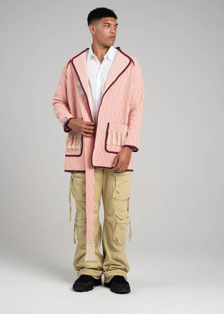 Person wearing a pink jacket and beige pants on a gray background