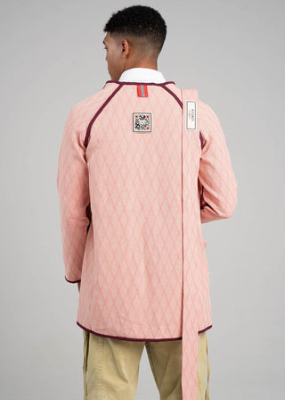 Person wearing a pink jacket with a QR code label on the back against a gray background