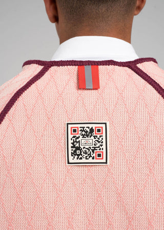 Close-up of a pink sweater with a QR code label on a gray background
