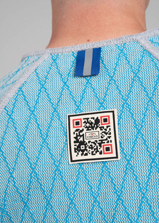 Close-up of a blue textured garment with a QR code label on a gray background