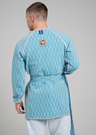 Person wearing a light blue patterned outfit with a QR code label on a gray background