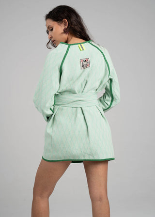 Woman wearing a light green dress with a belt on a gray background