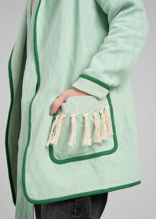 Green textured coat with a pocket featuring tassels on a gray background