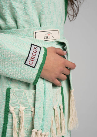 Green textured garment with tassels and 'Circus' branding on a plain background