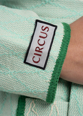 Close-up of a fabric with 'CIRCUS' label on a green and white textured background