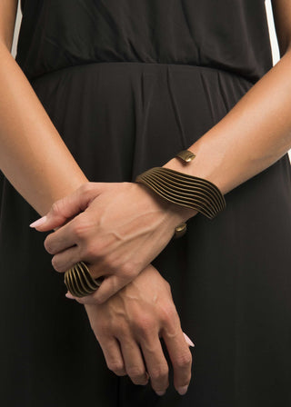 Person wearing a black dress with gold bracelets on wrists