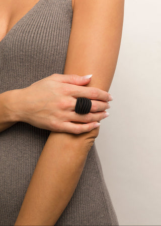 Person wearing a black ring on a neutral background