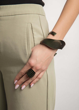 Hand wearing a black ring and bracelet on a plain background