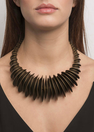 Woman wearing a unique bronze necklace against a neutral background