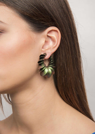 Close-up of a person wearing green spiral earrings with a neutral background