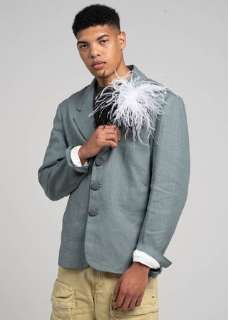 Man wearing a gray blazer with white feather details on a plain background