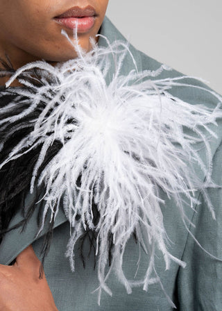 Person wearing a gray coat with a white feathered accessory.