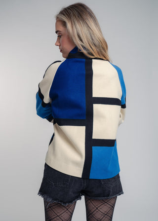 Person wearing a colorful geometric-patterned jacket on a plain background