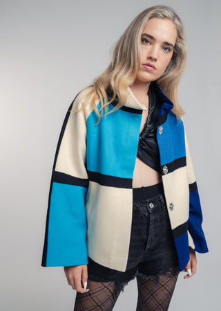 Woman wearing a colorful jacket with a plain background