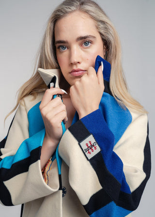 Woman wearing a colorful sweater with a patterned design on a gray background