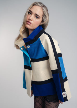 Woman wearing a colorful coat with a geometric pattern on a gray background