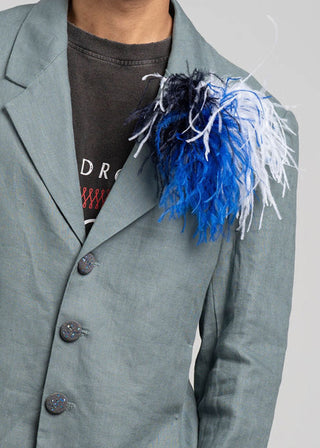 Gray blazer with a decorative feathered boutonniere on a plain background