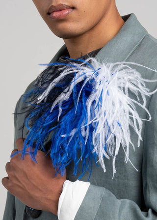 Person wearing a gray suit with a blue and white feathered boutonniere.
