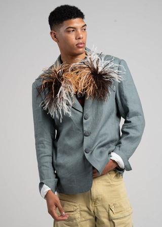 Man wearing a gray blazer with decorative elements on a plain background