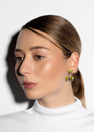 Woman wearing a white turtleneck and colorful earrings against a white background