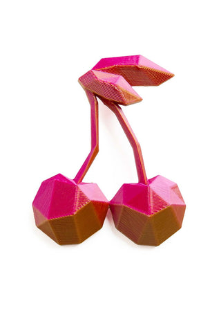 A pair of geometric cherry-shaped earrings in a vibrant magenta pink and metallic bronze finish, displayed on a clean white background.