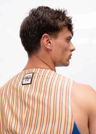 A man shown from the back wearing a sleeveless striped top with vertical red, orange, yellow, green, and blue stripes on a white background. A small square brand patch reading 'Euphorics' is visible on the upper back.