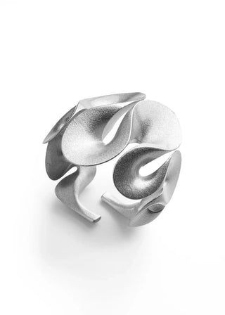 A sculptural silver ring with organic, flowing petal-like shapes and a matte-to-satin finish, photographed on a clean white background.