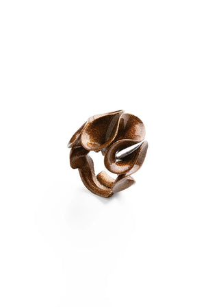 A sculptural, organic-shaped ring with a textured metallic bronze finish, photographed on a seamless white background.