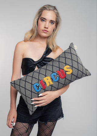 Woman holding a pillow with 'CIRCUS' letters against a gray background