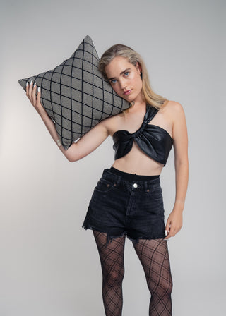 Woman in black outfit holding a geometric pillow against a white background
