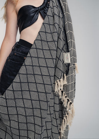 Person wearing a black and white patterned scarf with a plain background
