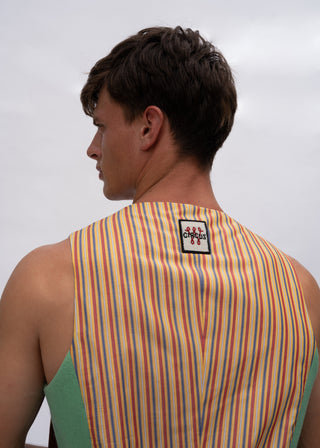 A man shown from the back wearing a sleeveless tank top with vertical multicolor stripes in orange, yellow, green, and blue over a light base, with a small black brand patch on the upper back.