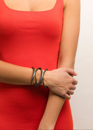Person wearing a red sleeveless top with a focus on a bracelet on a plain background