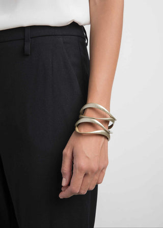 Person wearing multiple gold bracelets on a plain background