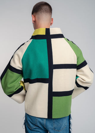Person wearing a colorful jacket with geometric pattern on a gray background