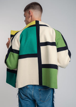 Person wearing a colorful geometric-patterned jacket on a plain background