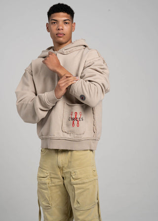 Man wearing a beige hoodie with a logo on a gray background