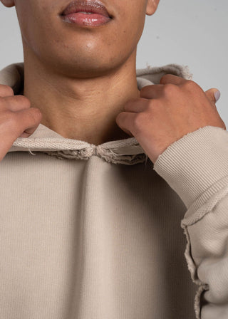 Person wearing a beige hoodie with a neutral background