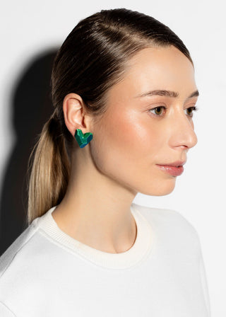 Woman wearing green earrings against a white background