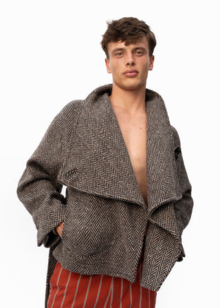 A male model wearing a brown and gray herringbone patterned open-front jacket or robe, paired with red and white vertically striped trousers, against a plain white background.