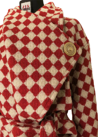 A close-up of a red and cream diamond-patterned fabric item, likely a hat or soft accessory, displayed on a black mannequin stand against a plain light background.
