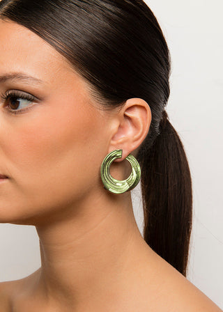 Woman wearing a gold hoop earring against a plain background