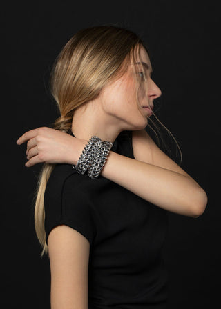 Woman wearing a silver chain bracelet on a black background
