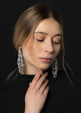 Woman wearing large silver hoop earrings against a black background